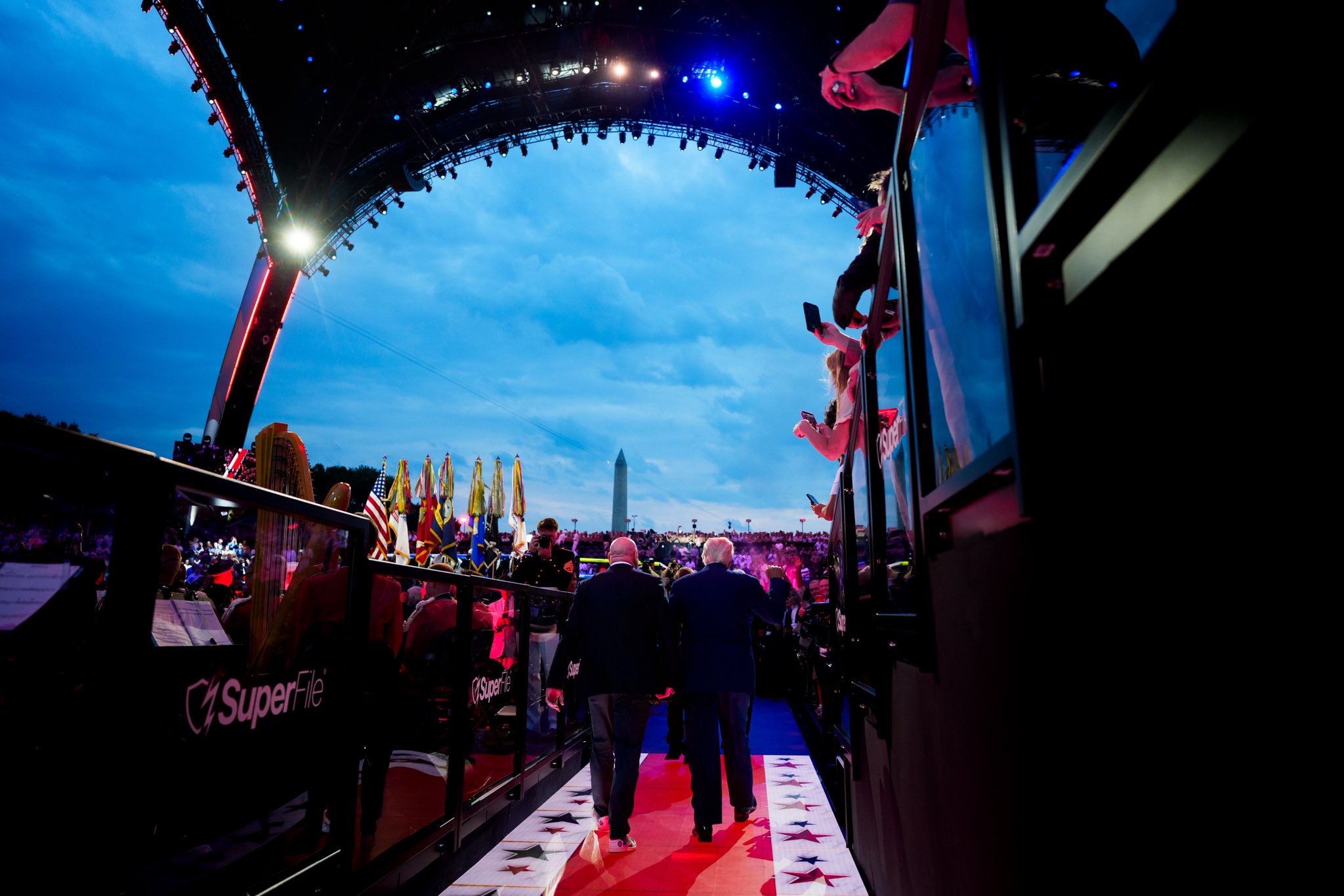 Evening event on the National Mall — flags and the Washington Monument framed by stage rigging